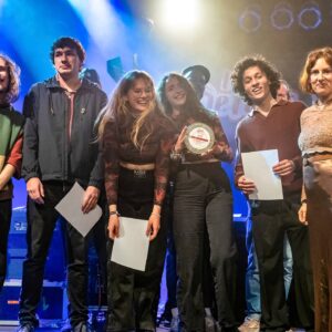 Zu sehen ist die Gewinner Band des local heroes Musikpreis 2022 "The Lifelines". Neben ihnen Vera Lüdeck, Geschäftsführerin der LAG Rock in Niedersachsen e.V.