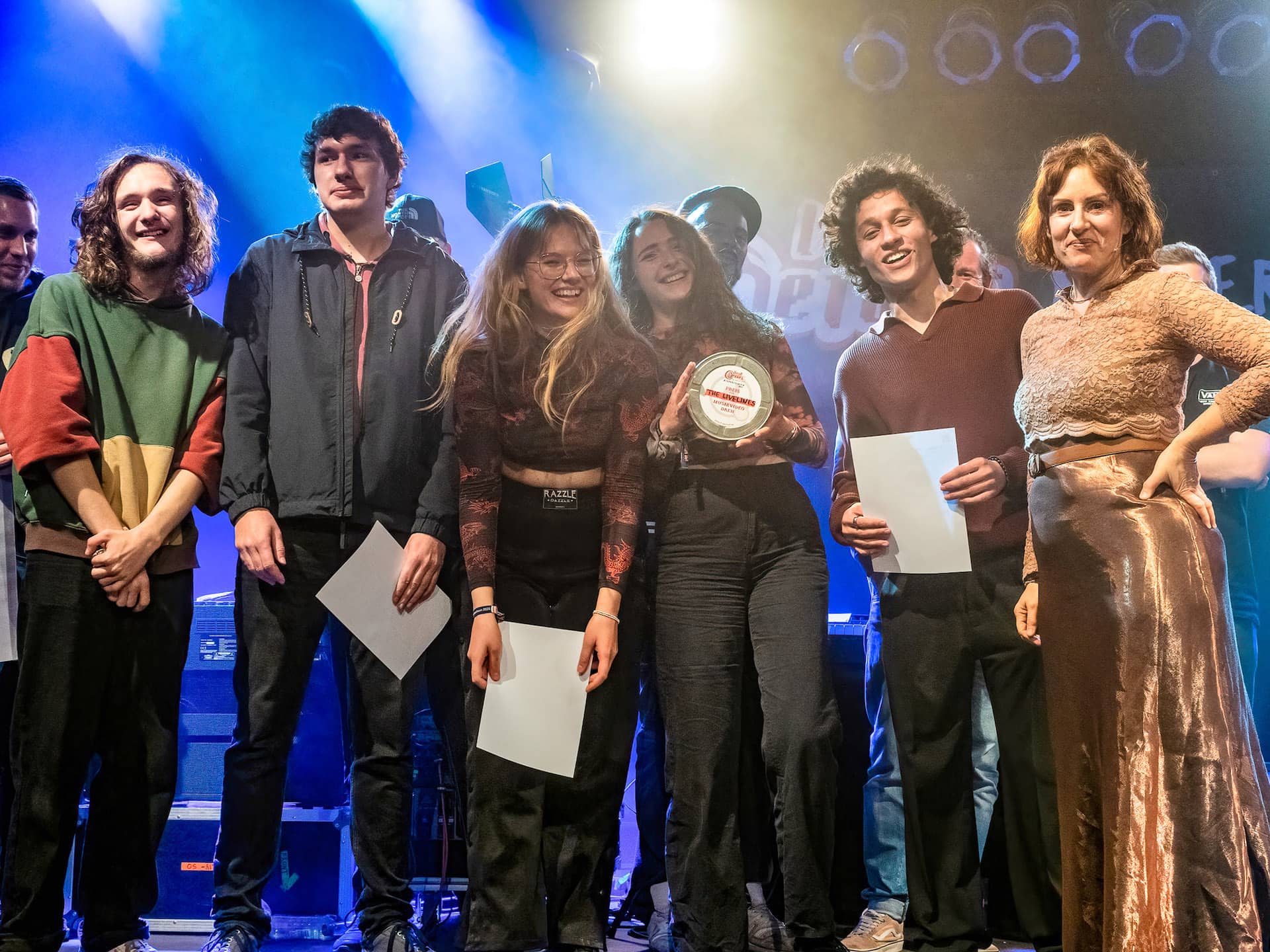 Zu sehen ist die Gewinner Band des local heroes Musikpreis 2022 "The Lifelines". Neben ihnen Vera Lüdeck, Geschäftsführerin der LAG Rock in Niedersachsen e.V.